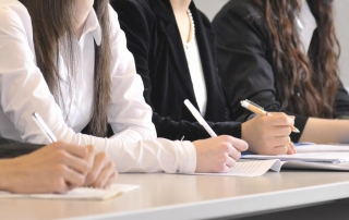 close-up of students taking notes in class
