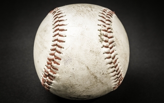 close-up of a well worn baseball on a black background