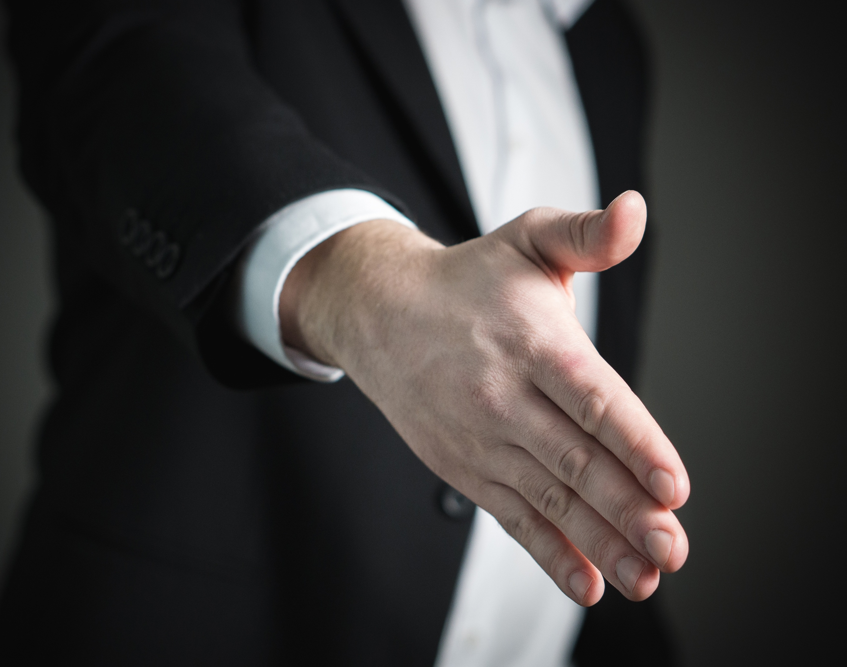 man in a suit reaching out for a handshake