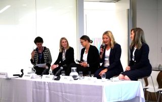 a panel of businesswomen sitting at a table with microphones